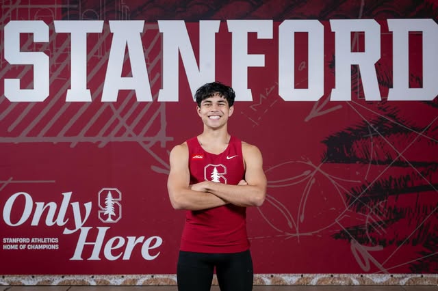 Joseph in a red Stanford track uniform in front of a Stanford backdrop